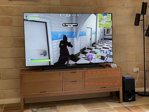 The closed media cabinet this project was built to cool, housing a PS5, Mac mini, Raspberry Pi, and other devices